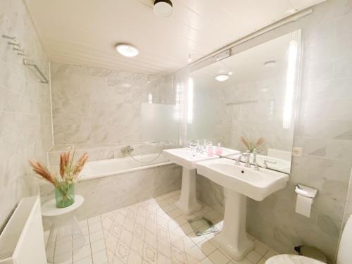 La salle de bains blanche est pourvue d'un lavabo et d'une baignoire. dans l'établissement Vakantieappartement Park Loverendale 3 Domburg DO23, à Domburg