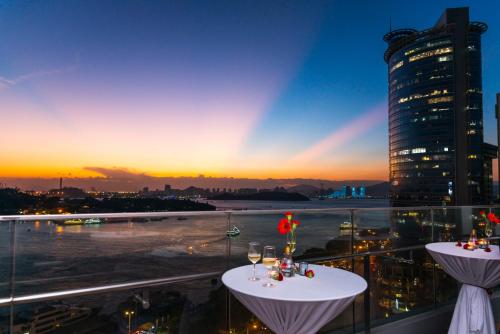 a view of a sunset from a balcony with wine glasses at Hotel Indigo Xiamen Harbour by IHG in Xiamen