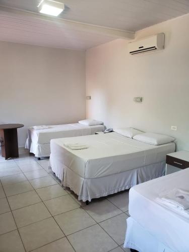 a hotel room with three beds in a room at Pantanal Hotel in Miranda