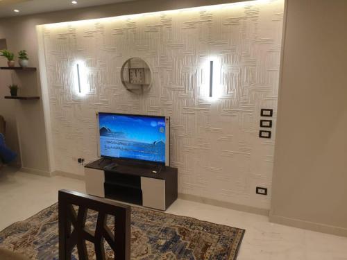 a living room with a tv on a wall at New Apartment AlMohandessin near Shehab street in Cairo