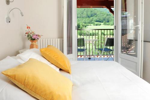 - un lit blanc avec des oreillers jaunes sur un balcon dans l'établissement Logis Hotel Xoko-Goxoa, à Saint-Michel