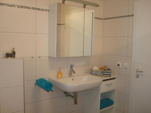 a white bathroom with a sink and a shower at Ferienwohnung Glückstein in Großeibstadt
