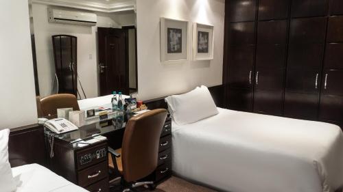 a room with two beds and a desk with a phone at Plaza São Rafael Hotel in Porto Alegre