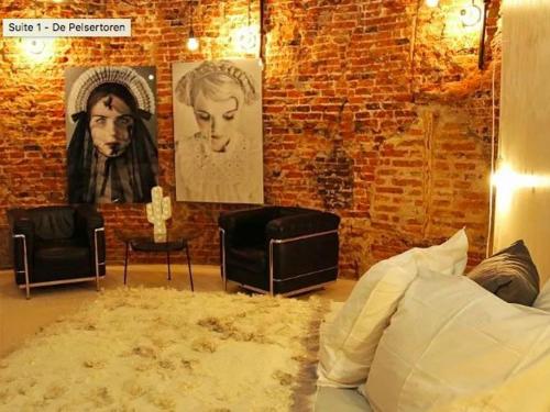 een slaapkamer met een bakstenen muur en een bed en een bank bij De Pelsertoren in Zwolle