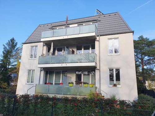 a white building with a balcony on the side of it at südausgerichtetes Apartment SüdWest Kleinmachnow in Kleinmachnow