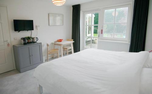 Un dormitorio con una gran cama blanca y una mesa en Bed & Bad Soet Texel, en Den Burg