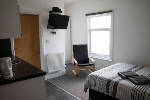 ein Schlafzimmer mit einem Bett, einem Stuhl und einem Fenster in der Unterkunft Bursar Street 21 in Cleethorpes
