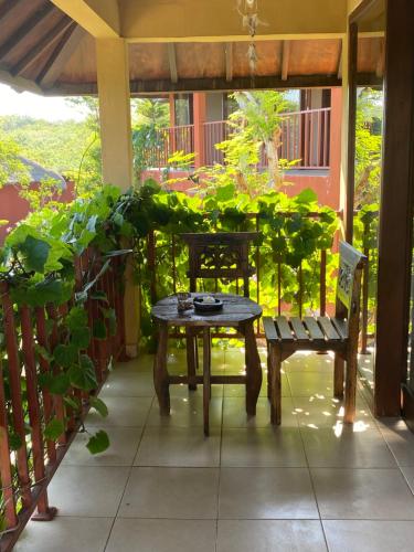 a table and a bench on a porch with plants at Villa Anjing 2 in Nusa Dua