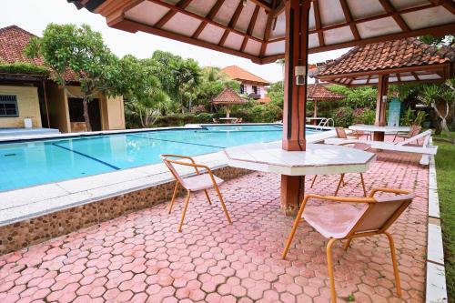 a patio with a table and chairs next to a swimming pool at Sari Bali Cottage in Kuta