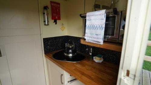 a kitchen counter with a sink and a microwave at Showman's Hut Westcote in Hawick