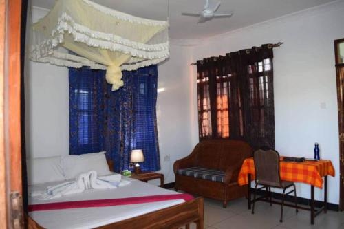 a bedroom with a bed and a chair and a desk at Remarkable 10-Bed Cottages in Bagamoyo in Bunju