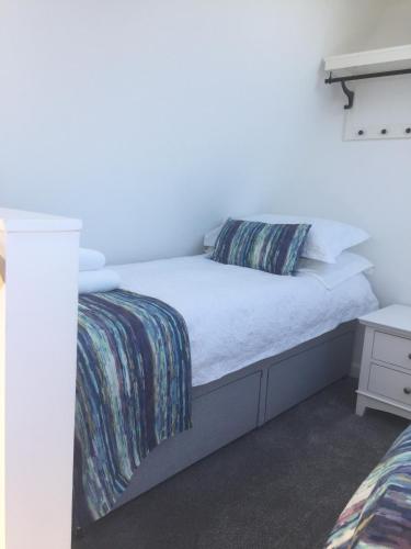 a bedroom with a bed with a white bedskirtspectspectssenalsenalsenalsenal at Cosy sea view cottage Isle of Skye in Colbost