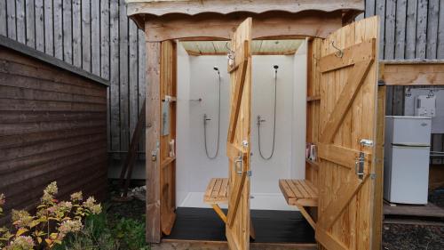 uma casa de banho em madeira com quatro cabinas de duche num edifício em Shepherd's Hut Westcote em Hawick