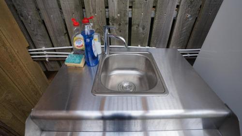 a stainless steel kitchen sink with cleaning products on it at Shepherd's Hut Westcote in Hawick