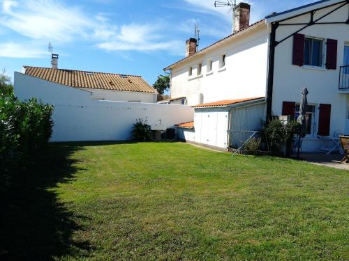a yard in front of a white building with a grass field at Maison spacieuse près de Marennes-Hiers-Brouage (90 m²) in Marennes