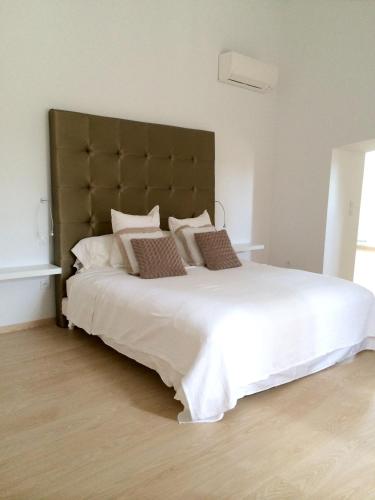 une chambre avec un grand lit blanc avec une grande tête de lit dans l'établissement Maison charmante à Montauriol avec jardin et piscine privée., à Montauriol