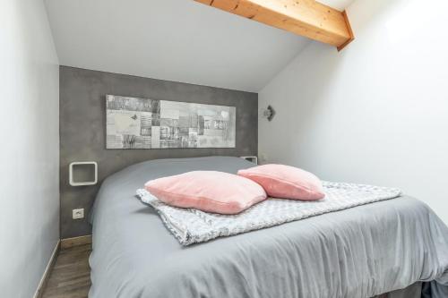 a bedroom with a bed with two pink pillows at Maison charmante à Poussan avec jardin privé in Poussan