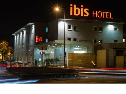 a hotel with a lit up sign on a street at night at Hotel ibis Guimaraes in Guimarães