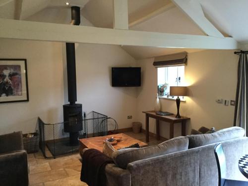 a living room with couches and a wood stove at Barn Owl Lodge at Millfields Farm Cottages in Ashbourne