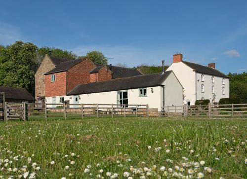 a field of grass with a white house and a fence at Barn Owl Lodge at Millfields Farm Cottages in Ashbourne
