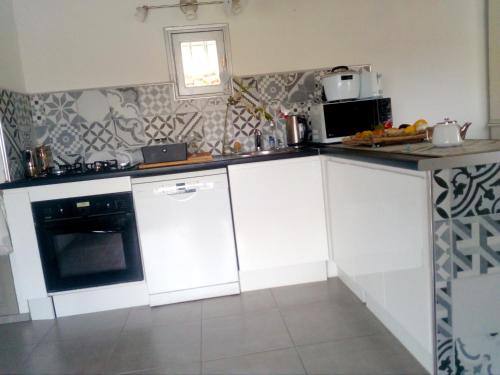 une cuisine avec des armoires blanches et un four à plaques de cuisson dans l'établissement Maison accueillante à Toulon - Jardin privé 90 m², à Toulon