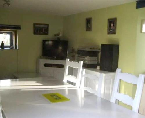 Sala de estar con 2 sillas blancas y TV en Appartement d'une chambre avec jardin clos et wifi a Hirel, en Hirel