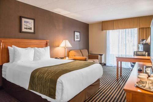 a hotel room with a large bed and a chair at Comfort Inn in Brockville