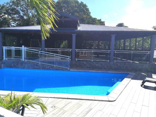 a large blue swimming pool next to a house at Appartement spacieux avec jardin et piscine à Lamentin, 97 m² in Lamentin