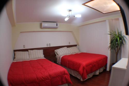 a room with two beds with red covers in it at Residencial Victoria Said in Linares