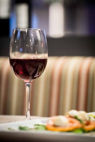 a glass of red wine next to a plate of food at Mercure Sao Jose dos Campos in São José dos Campos