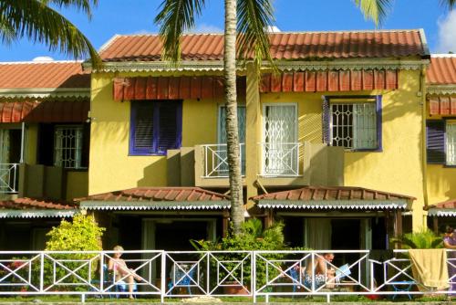 a yellow building with palm trees in front of it at 2 bedrooms appartement at Grand Baie 10 m away from the beach with sea view enclosed garden and wifi in Grand-Baie