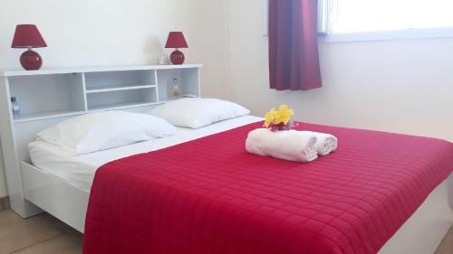 a bed with a red blanket and a stuffed animal on it at Appartement spacieux avec vue sur mer, Le Vauclin, 79 m² in Le Vauclin