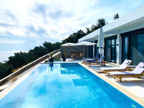 a swimming pool with chairs and a house at Villa ECO LUXE in Sivota