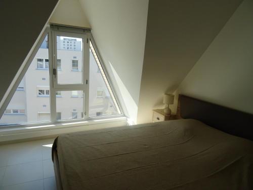 ein Schlafzimmer mit einem Bett und einem großen Fenster in der Unterkunft Appartement de 2 chambres avec vue sur la mer et balcon amenage a Berck in Berck-sur-Mer