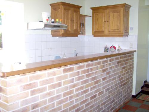 - une cuisine avec un mur en briques et des placards en bois dans l'établissement Maison accueillante à La Chapelle-aux-Choux avec jardin spacieux 70 m², à La Chapelle-aux-Choux