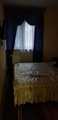 a bedroom with a bed with a blue curtain and a window at Apartmani Kadunić in Bugojno