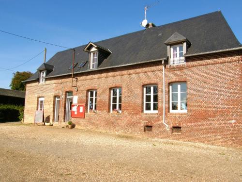 un bâtiment en briques rouges avec un toit noir dans l'établissement Maison de charme à Berville avec jardin non clôturé, à Berville
