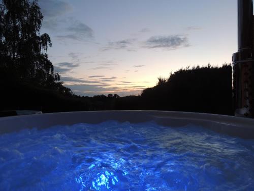 une baignoire remplie d'eau bleue avec un coucher de soleil en arrière-plan dans l'établissement Au Chalet Bain Nordique neuf indépendant calme assuré, à Hazelbourg
