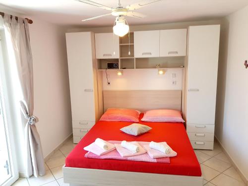 a bedroom with a red bed with two pillows at Charming Apartment in Pag with Sea View, 40 sqm in Pag