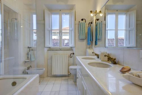 a bathroom with three sinks and a tub and a toilet at Spacious Apartment in Forte dei Marmi - Sea View & Balcony in Forte dei Marmi