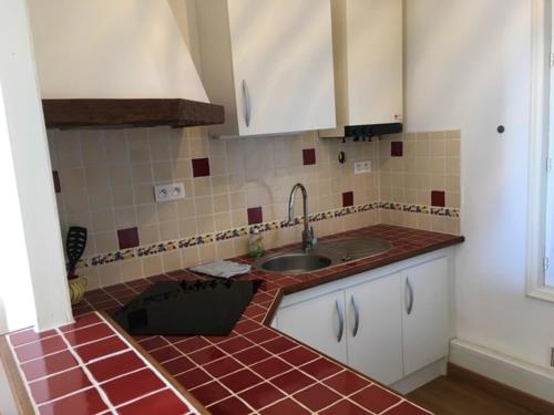 a kitchen with a sink and a red tiled floor at Appartement spacieux avec vue sur la mer - 70 m² à Mers-les-Bains in Mers-les-Bains