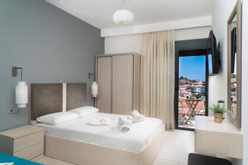 a bedroom with a white bed with a large window at Atoli Studios in Skala Marion