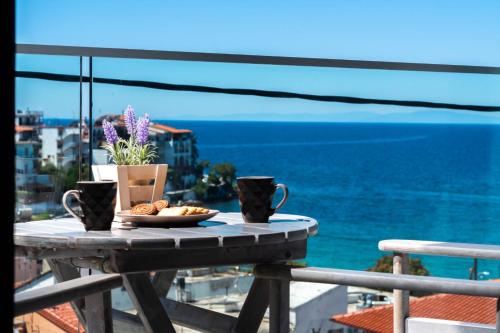 a table with a plate of food on a balcony with the ocean at Atoli Studios in Skala Marion