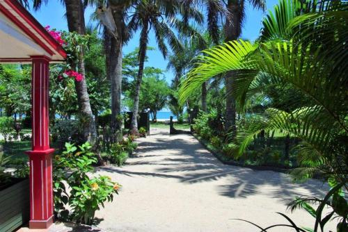 a pathway with palm trees and a red pole at Charming Studio in Foulpointe, Sea View and Garden, 30 m² in Foulpointe