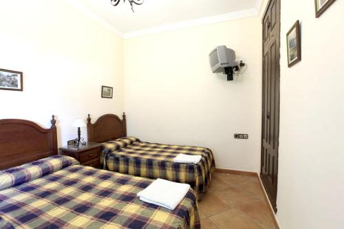 um quarto de hotel com duas camas e uma televisão em 4 bedrooms villa with private pool enclosed garden and wifi at Sanlucar la Mayor em Sanlúcar la Mayor