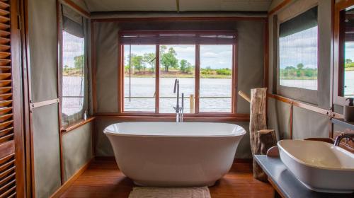 ein Badezimmer mit einer großen Badewanne und einem Waschbecken in der Unterkunft Ndhovu Safari Lodge in Mahango