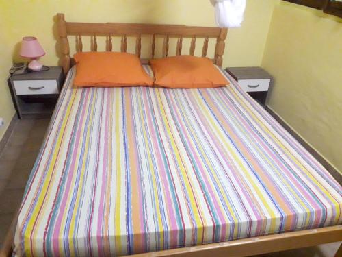 a bed with a colorful striped bedspread and two tables at Maison charmante à Sainte-Anne in Sainte-Anne