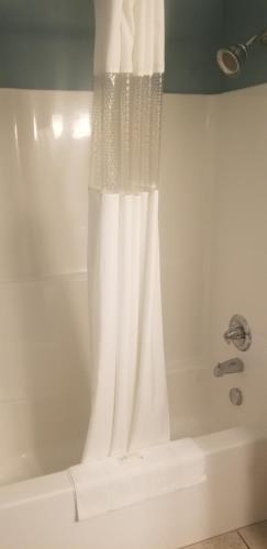 cortina de ducha blanca en una bañera blanca en Suburban Studios Quantico, en Stafford