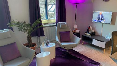 Friesenhof Nieblum - Hotel Garni في نيبلوم: غرفة معيشة مع كرسيين وتلفزيون