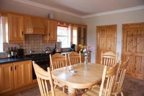 a kitchen with a wooden table with chairs and a table and a table at Inviting 4-Bed House in Strokestown in Grange